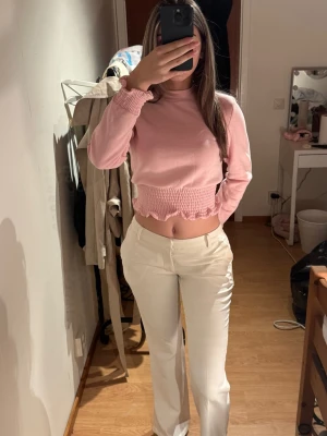 Ljusrosa stickad topp med volang - Supersöt ljusrosa stickad topp med långa ärmar och volangdetaljer i nederkant och vid ärmslut. Helt ny!💕