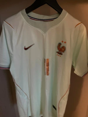 Frankrike fotbollströja Olise #11 - Snygg vit fotbollströja från Nike med Frankrikes landslagsemblem och två stjärnor på bröstet. Tröjan har röda och blå detaljer, samt namn och nummer 'OLISE 11' på ryggen. Perfekt för match eller träning.