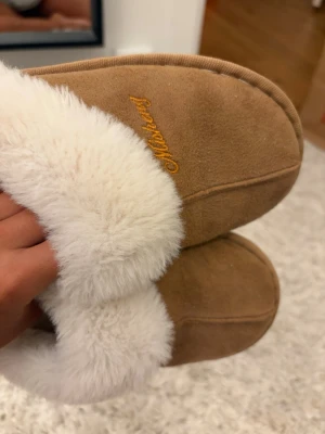 Bruna tofflor med vit päls - Supersköna tofflor gjorda i mockaliknande material. Väl använda, men fortfarande lika mjuka som nya 💗Står storlek 38/39, men tycker själv de är små i storleken för mig som vanligtvis har 38 💕 