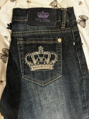 Victoria Beckham Rock & Republic jeans - Mörkblå jeans med snygg kronbrodyr på bakfickan och kontrastsömmar. Klassisk femficksmodell i denim med exklusiv känsla och detaljerad patch i läder bak. Perfekta för dig som vill sticka ut med coola detaljer. Gärna kom med olika pris förslag!💕W27