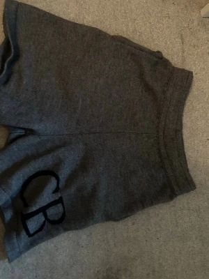 Mörkgrå mjuka shorts Cole butler  - Mörkgrå shorts i mjukt material med elastisk midja och två bakfickor. På ena benet finns en broderad detalj med bokstäverna 'CB'. Perfekta för chill dagar eller träning. Bra kvalitet och helt nya