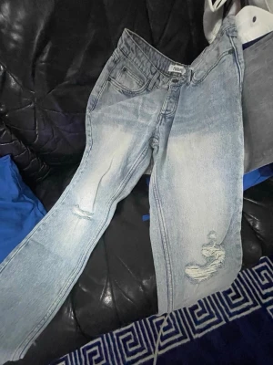 Ljusblå ripped jeans från fsbn - Säljer ett par ljusblå jeans från fsbn med slitna detaljer och hål på benen. Jeansen har klassisk femficksmodell och raka ben. Perfekta för en avslappnad och trendig look. Materialet är denim i bomull.