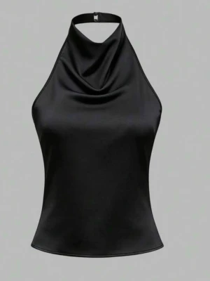 Svart halterneck topp i satin - Snygg svart halterneck topp i satin med draperad front och tunna snören som knyts i ryggen. Toppen har en elegant siluett och stängs med ett spänne i nacken. Perfekt för dig som vill ha en stilren och trendig look.