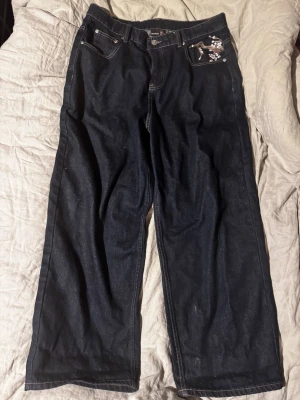 Blå derschutze jeans - Mörkblå derschutze jeans med brodering på fram och baksida. Baggy och unik design
