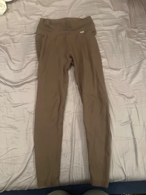 Ribbade bruna leggings från Aim'n - Supersnygga ribbade leggings från Aim'n i en jordnära brun färg. De har hög midja och är tillverkade i ett stretchigt material som sitter skönt på kroppen. Perfekta för dig som vill ha både stil och komfort i vardagen.