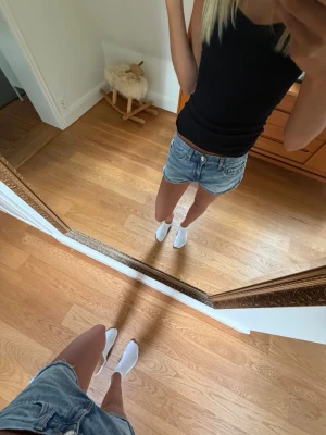 Blå denimshorts med rå kant - Säljer ett par klassiska blå jeansshorts i denim med rå kant nertill och femficksmodell. Shortsen har normal passform och midja, perfekt till sommaren. Snygg tvättad look och tidlös stil.