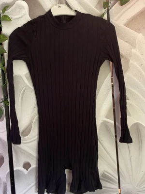 Svart ribbad långärmad body - Säljer en svart, ribbad body med lång ärm och rund hals. Bodyn har en tight passform och är tillverkad i ett stretchigt material som sitter snyggt på kroppen. Perfekt att styla med jeans eller kjol för en clean look.