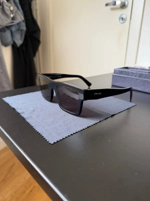 Prada solglasögon  - Prada solglasögon köptes augusti 2024. Bara använda under resor men inte så ofta. Ny priset ligger över 3000kr. Svarta bågar med svart glas. Digitaltkvitto finns via intresse. 