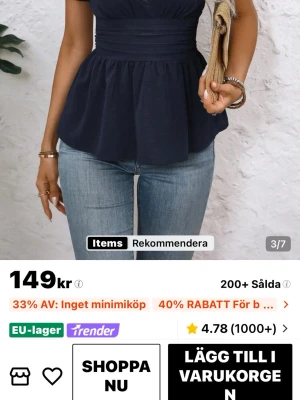 Mörkblå v-ringad blus med volang - Snygg mörkblå blus med v-ringning och markerad midja. Toppen har volang nedtill och korta ärmar, perfekt att styla med jeans eller kjol. Enkel men chic design som passar till många tillfällen.