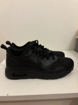 Svarta Nike Air Max sneakers - Säljer ett par helsvarta Nike Air Max sneakers med klassisk låg profil. Skorna är använda 2 ggr och säljer dem pågrund av att dem inte passar längre. Perfekt för dig som är ute efter ett par stilrena skor men ändå lite mer piffiga.