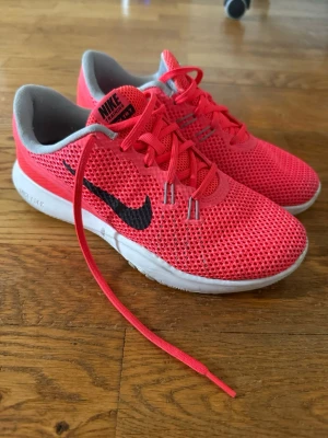 Nike rosa sneakers - Snygga sneakers från Nike i en stark rosa färg. Ovandelen är i ventilerande mesh och skorna har vita sulor samt rosa skosnören. Perfekta för dig som vill sticka ut med färg och sportig stil.