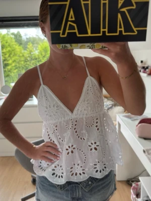 Vit broderad topp med spets - Superfin oanvänd vit linnetopp med broderade blommor och spetsdetaljer. Den har v-ringning, smala axelband och en luftig passform. Nypris: 359kr🤍