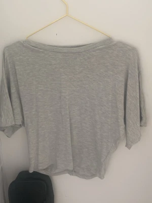 Ljusgrå loose topp med kort ärm - En enkel och stilren ljusgrå topp med loose passform och korta ärmar. Tillverkad i mjukt bomullsmaterial, perfekt för en avslappnad look. Passar till det mesta och är superbekväm att bära.