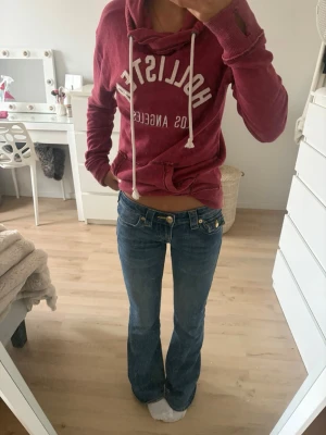 Blå bootcut jeans ifrån true religion  - Säljer ett par blå bootcut jeans med låg midja och dekorativa guldknappar fram och på bakfickorna. Jeansen har klassisk femficksdesign och är tillverkade i ett mjukt denimtyg.