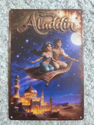 Disney Aladdin metallskylt - Snygg metallskylt med motiv från Disneyfilmen Aladdin. Skylten visar Aladdin och Jasmine på en flygande matta över ett upplyst palats i natten. Färgerna är blå, guld och brons. Skylten har fyra hål i hörnen för enkel upphängning.