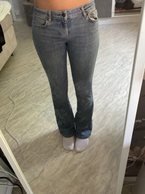 Blå bootcut jeans med låg midja - Säljer ett par klassiska blå bootcut jeans med låg midja och fem fickor. Jeansen har en snygg tvättad look och raka ben som går ut lite nedtill. Perfekta till vardags och passar till det mesta i garderoben.