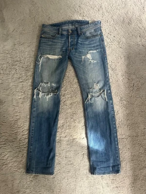 Diesel jeans  - Säljer ett par snygga bootcut diesel jeans med snygga slitningar. Riktigt sköna fades på dom och inga fläckar eller liknande. Hör av er vid funderingar. 