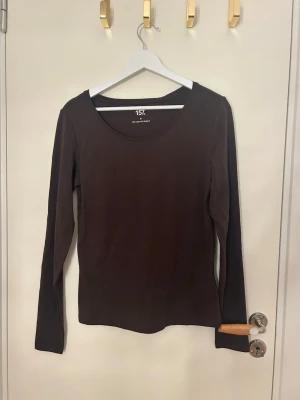 Brun långärmad topp från 157 - En basic brun långärmad topp från 157 med rund halsringning. Enkel och stilren design i mjukt material, Snygg passform och skön att bära hela dagen.
