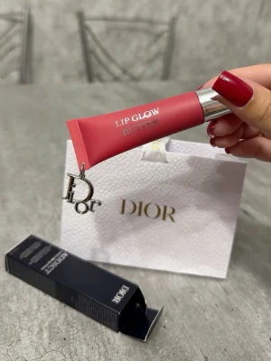 Dior Lip Glow läppglans #105 Lychee - Lyxigt läppglans från Dior i en snygg rosa nyans. Tuben har silverfärgat lock och en elegant Dior-berlock som detalj. Kommer i originalförpackning och presentpåse. Perfekt för dig som vill ha glansiga och återfuktade läppar med en hint av färg.
