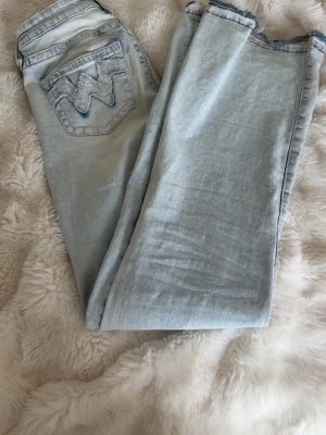 Ljusblå jeans med bakficka - Snygga ljusblå jeans med klassisk femficksdesign och en tydlig W-detalj på bakfickan. Jeansen har raka ben och är tillverkade i denim med en lätt tvättad look. Perfekta för en avslappnad stil.