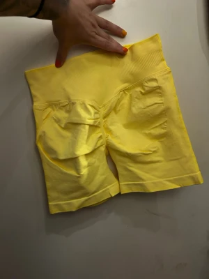 Gula högmidjade shorts - Snygga gula cykelshorts med hög midja. Shortsen är stretchiga och har en tight passform som framhäver formerna. Perfekta för träning eller en sportig look.