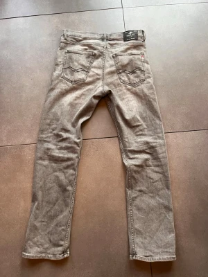 Grå replay jeans herr - Säljer ett par grå jeans med rak passform och klassisk femficksdesign. Jeansen har normal midja och dragkedjegylf. Materialet är denim i bomull och färgen är tvättad grå, vilket ger en avslappnad look. Perfekta till en enkel t-shirt eller hoodie. Jag är ca 175cm lång och de passar galant.
