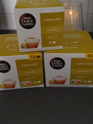 Nescafé Dolce Gusto Cappuccino kapslar - Tre förpackningar Nescafé Dolce Gusto Cappuccino kapslar. Två av lådorna innehåller 15 kapslar och en innehåller 8 kapslar. Förpackningarna är vita och gula och passar till Dolce Gusto-maskiner. Den med 8 st är testad 