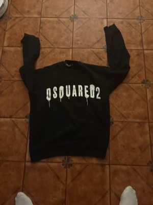Svart sweatshirt från Dsquared2 - Cool svart sweatshirt från Dsquared2 med stor vit logga framtill. Tröjan har rund halsringning och långa ärmar. Perfekt för dig som gillar streetwear och vill sticka ut med en snygg logga. Materialet känns mjukt och bekvämt mot huden.