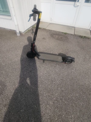 Svart elscooter med grå detaljer - Säljer en svart elscooter med grå handtag och röda detaljer på bromskabeln. Scootern har en bred fotplatta och ringklocka på styret. Perfekt för att ta sig runt i stan på ett smidigt sätt.