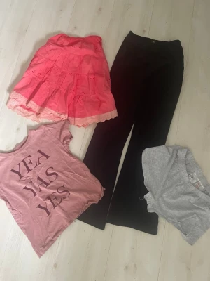 Rosa t-shirt med tryckPlyschbyxor+Grå shorts  - Trendig rosa t-shirt med texten 'YEA YAS YES' i stora bokstäver framtill. T-shirten har korta ärmar och rund halsringning. Perfekt för en avslappnad och cool stil.Plysvhbyxor + Hrå små shorts +’Bomull spets kjol 