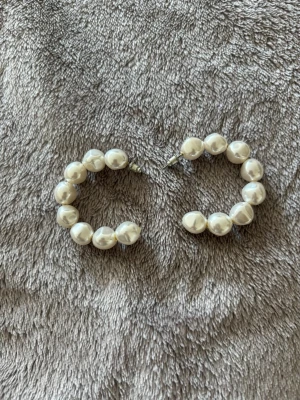 Stora creolörhängen med pärlor - Säljer ett par stora creolörhängen med vita pärlor. Örhängena har en rund form och är täckta av glansiga pärlor som ger en klassisk och trendig look. 