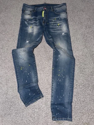 Blå dsquard2  jeans med färgstänk och slitningar - Säljer dsquard2 jeans blå med färg stänkar storlek 46