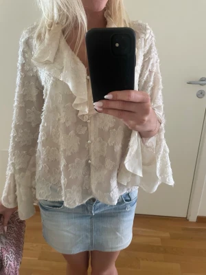 Vit volangblus med spets från Zara - Vit blus från Zara med volangkant och spetsmönster. Blusen har vida ärmar och knappar framtill. Passar till allt! Den är storlek xs men passar även S! Tveka inte att skriva till mig om frågor eller prisförslag!