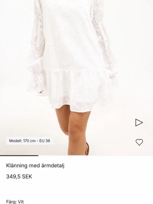 Vit blommig spetsklänning - Söt vit kortklänning med blommigt spetsmönster och volangdetalj nedtill. Klänningen har långa, transparenta ärmar och en lös passform.
