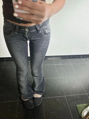 Bootcut jeans med dekoration - Säljer mina lågmidjade svart/gråa jeans ifrån gina. De är knappast använda, som nya. Inga märken på användning. De är i storlek XS                    Priset kan såklart diskuteras!😊