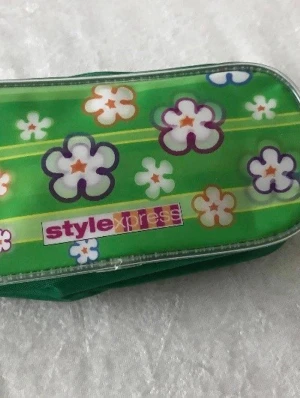 3D Motiv Pennfodral  - Säljer ett grönt pennfack med blommigt mönster från Stylexpress. Pennfacket har dragkedja och är gjort i tyg med plastad framsida. Perfekt för att förvara pennor eller småprylar i väskan. Färgglad och retro design med vita, orange och lila blommor. 59kr/st , finns fler kvar, samma frakt 