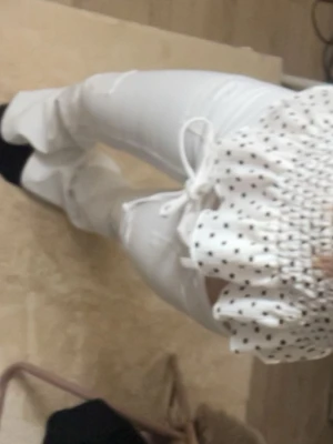 Vita utsvängda jeans med snörning - Säljer ett par vita jeans med utsvängda ben och snörning i midjan. Jeansen har slitna detaljer vid knäna och är tillverkade i ett stretchigt material. Perfekta för dig som gillar en trendig och unik look.(oanvända)