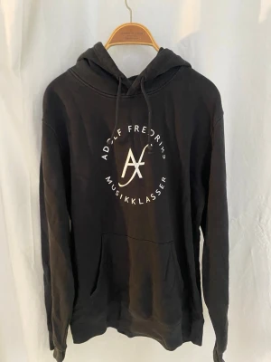 Merch för Adolf Fredriks Musikklasser! - Använd, men fortfarande helt okej. Merch köpt från Musikskolan. Trycket på framsidan är lite spucket efter att ha blivit använd. Till barn.