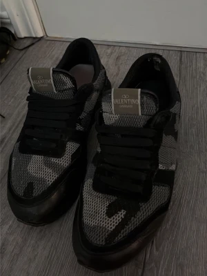 Valentino rockrunners - Snygga sneakers från Valentino i svart och grått med camomönster. Skorna har mesh- och mockadetaljer samt svarta skosnören. Låg modell som passar perfekt till streetwear och casual outfits.