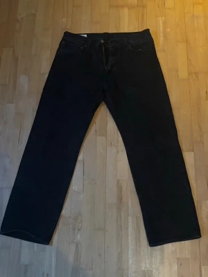 Svarta raka jeans - Säljer ett par svarta jeans med rak passform och klassisk femficksdesign. Jeansen har normal midja och är tillverkade i ett robust denimtyg. Perfekta för dig som gillar en enkel och stilren look.