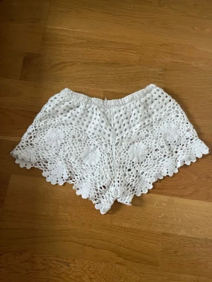 Vita virkade shorts med spetsdetaljer - Säljer ett par vita virkade shorts med fina spetsdetaljer i storlek 36/38.