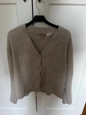 Beige kofta med knappar - Mysig beige kofta med v-ringning i storlek xs. Koftan är dock oversized så skulle säga att den sitter som en M/L