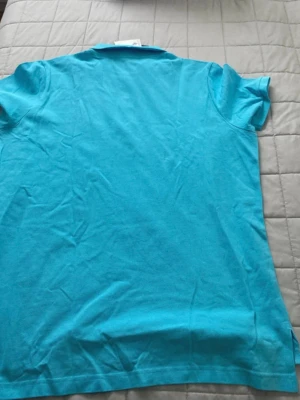 Turkos pikétröja från U.S. Polo Assn. - Snygg turkos pikétröja från U.S. Polo Assn. i klassisk modell med krage och korta ärmar. Perfekt till jeans eller shorts för en fräsch look. Tillverkad i mjuk bomull som känns skön mot huden. Helt ny, aldrig använd.