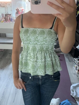 Grön topp - Säljer en jätte Söt grön linnetopp med vitt blommönster. Toppen är från Gina tricot i storlek S och går att göra till Tubtopp.💕