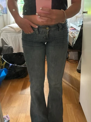 Blå bootcut jeans med låg midja - Säljer ett par klassiska blå bootcut jeans med låg midja och femficksmodell. Jeansen har en lätt tvättad look och är i ett mjukt denimtyg som sitter snyggt över höfterna och låren innan de släpper ut vid bensluten. Perfekta till sneakers eller boots!