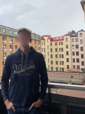 Vintage Tom tailor hoodie - Snygg mörkblå hoodie med stor vit text och tryck på bröstet. Hoodien har huva med vita snören och en klassisk magficka framtill. Perfekt för en avslappnad och cool stil. Passar M men står L, hör av dig vid funderingar! Modell 184cm