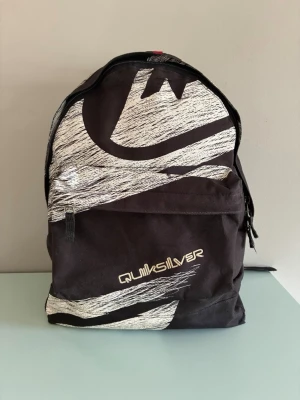 Quiksilver ryggsäck  - Quiksilver ryggsäck. Slitet skick, hål i hörnen längst nere och materialet inuti har flagna.