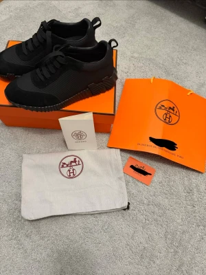 Svarta sneakers från H - Snygga svarta sneakers från H  med ovandel i mesh och mockadetaljer. Skorna har en chunky sula med cool struktur och klassiska svarta skosnören. Kommer med originalkartong, dustbag och H-påse. Perfekta för dig som gillar exklusiv och stilren design.