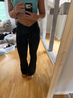 Svarta bootcut leggings - Säljer ett par svarta leggings med bootcut-modell och V-formad midja. De är stretchiga och sitter tight över höfterna, vilket ger en snygg siluett. Perfekta för dig som vill ha bekväma men ändå trendiga leggings.