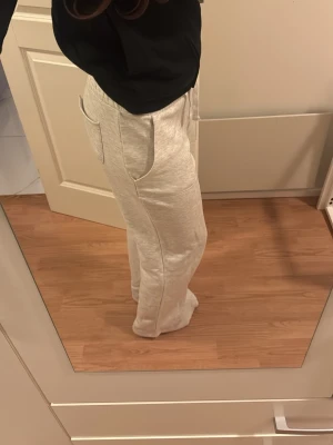 Ljusgrå mjukisbyxor med dragsko - Säljer ett par ljusgrå mjukisbyxor med raka ben och dragsko i midjan. Byxorna har stora fickor fram och är gjorda i ett mjukt, stretchigt material som känns riktigt skönt. Väldigt bekväma.